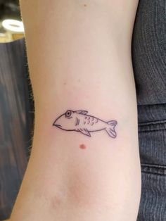 a small fish tattoo on the left side of the arm is shown in black ink