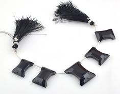 a necklace with black beads and tassels hanging from it's sides on a white background