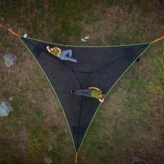 two people laying on top of a black tarp