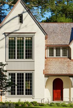 a white house with red door and windows in the front yard, on a sunny day