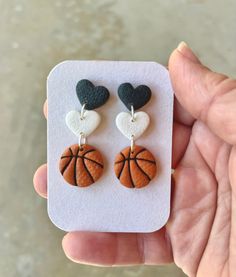 a pair of earrings in the shape of a basketball ball with heart shaped dangles