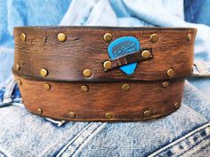 "Brown leather belt with two shades of brown two pieces on the front and storage for guitar pick with bronze studs around the belt and bronze buckle. The perfect gift for people who have style and love fashion as well as musicians and guitarists. A belt with a unique design in the style of the Wild West. ISHAOR is an international fashion brand that specializes in leather and boasts exclusive and groundbreaking designs that have become highly popular around the world. The brand was established i Adjustable Leather Belt Buckles With Rivets, Vintage Brown Belt With Rivets, Vintage Brown Belts With Rivets, Adjustable Brown Belt With Rivets, Brown Two Piece, Leather Wristbands, The Wild West, Shades Of Brown, Brown Leather Belt