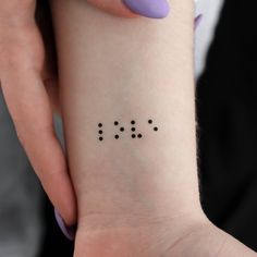 a woman's wrist with four dots on it and the word love written in black ink