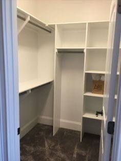 an empty walk in closet with white shelving and carpeted flooring on the ground