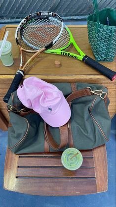 two tennis rackets, a water bottle and a purse on a table with other items