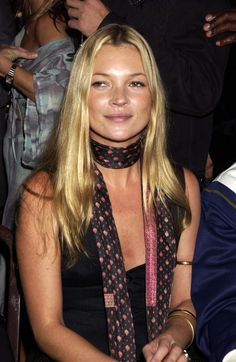 a woman sitting in front of a group of people wearing scarves and necklaces