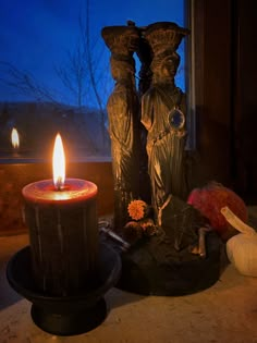 two statues sitting next to each other near a candle