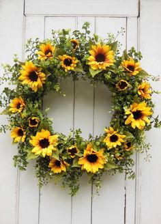 a wreath with sunflowers hanging on a white door