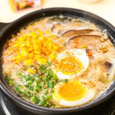 a bowl filled with soup and eggs on top of a table