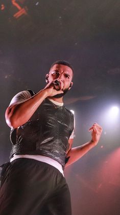 a man standing on top of a stage holding a microphone in his hand and singing