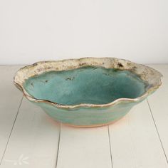 a green bowl sitting on top of a white table next to a wooden floor and wall