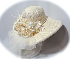 "This creamy ivory summer bridal hat with a Victorian flair has a crown covered in satin Venise lace with a gorgeous pearl trim on the brims edge and around the crown bottom. Ivory organdy ribbon falls in long tails in back along with ivory crushed tulle that forms a soft bow & long tails. Satin creamy ivory roses studded with pearls and hydrangeas fill the bouquet in back. Ivory biot feathers tuck behind the flowers on one side. A beautiful, romantic summer wedding accessory! The hat measures 2 Ribbon Falls, Romantic Summer Wedding, Hats Summer, Romantic Summer, Ivory Roses, Elegant Hats