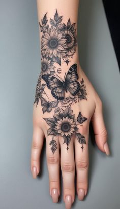 a woman's hand with flowers and butterflies tattooed on the wrist, which is black