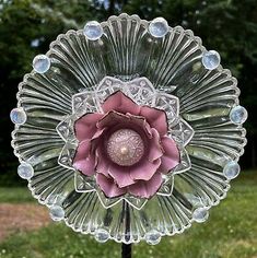 a glass flower on top of a metal stand in the grass with bubbles around it