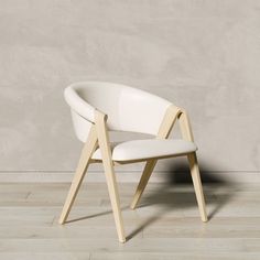 a white chair sitting on top of a hard wood floor next to a gray wall