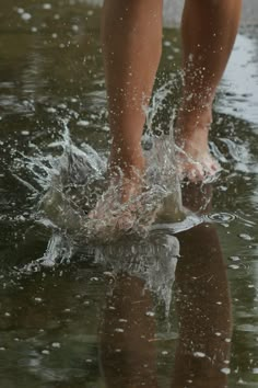 a person standing on top of a puddle with their feet in the water and splashing around