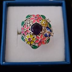 This Amethyst And Enameled Flower Ring Is Beautifully Crafted With A Round Amethyst Gemstone, Being The Center Of Attention It Is Designed Like A Bouquet Of Flowers And Is Beautifully Surrounded By Enameled Flowers, Leaves, And A Beautiful Butterfly. Each Is Accented With Different Gemstones Like Rubies, Yellow Sapphires, And White Zircons This Unique Ring Also Has A Signature Blue Sapphire In A Star Under The Beautiful Open Gallery Center Amethyst Is Approx 1.60 Ctw