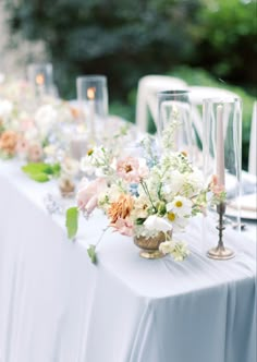 the table is set with flowers, candles and glass vases for an elegant look