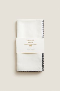 the white napkin with black trim is folded in front of a plain background and has a label that reads seveletta serenity