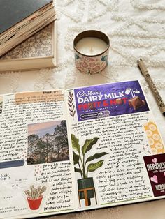 an open book with pictures on it next to a candle and some papers that have been placed in front of them