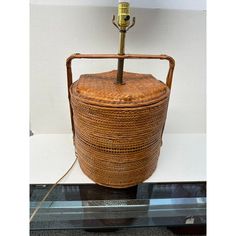 a wicker basket with a lamp on top in a display case at a museum