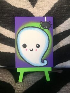 a painting of a ghost with a spider on it's head sitting on a small easel