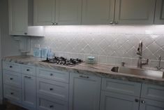 a kitchen with white cabinets and marble counter tops