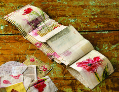 an open book with flowers on it sitting on top of a wooden table next to papers