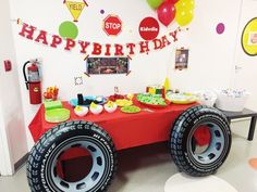 a birthday party with a monster truck table and balloons on the wall, along with decorations