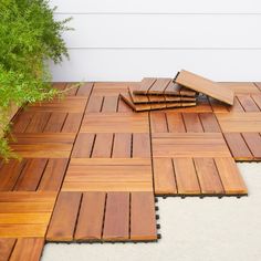 a wooden deck with several pieces of wood laid out on top of it and some plants in the background