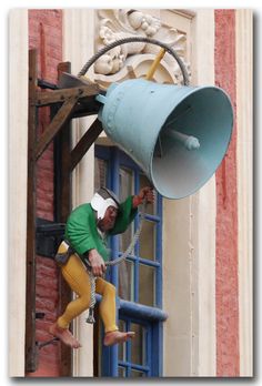 a man climbing up the side of a building while holding onto a large metal object