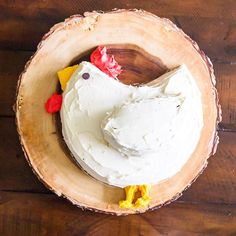 a cake decorated like a chicken sitting on top of a wooden bowl