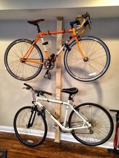 two bikes are mounted to a pole on the wall in front of a bike rack