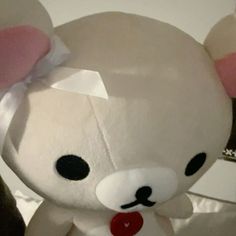 a white stuffed animal with a bow on it's head and ears, sitting in front of a mirror