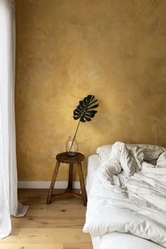 a bedroom with a bed and a plant on the side table in front of it