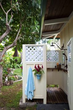 an outdoor shower is shown with flowers in the pot and towels hanging on the door