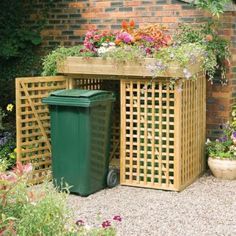 a green trash can sitting next to a wooden planter