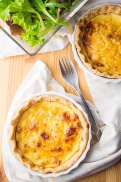 two pies sitting next to each other on top of a table with salad in the background