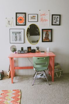 a desk with a mirror, chair and pictures on the wall above it in a room