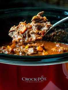 a spoon full of beef stew in a crock pot