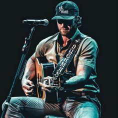 a man sitting in front of a microphone while holding a guitar