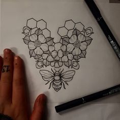 a drawing of a bee and flowers on white paper with black marker pens next to it