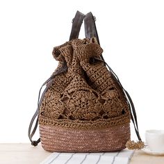 a brown crocheted bag sitting on top of a table next to a cup