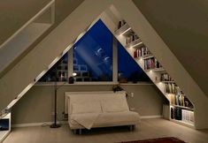 a bed sitting under a window next to a bookshelf filled with lots of books