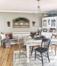 a dining room table with chairs and a bench in front of the window, decorated for christmas