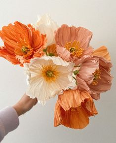 a person is holding an orange and white flower bouquet