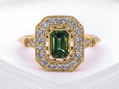 an emerald colored stone surrounded by white and yellow diamonds in a gold ring with diamond accents