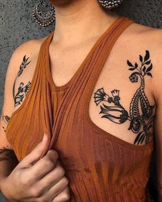 a woman with some tattoos on her chest and arm is holding something in her hand