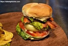 a bacon, lettuce and tomato sandwich on a wooden platter with chips