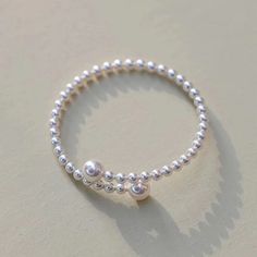 Experience elegance redefined with our "Eternal Embrace" White Freshwater Pearl Bracelet. Two large pearls gracefully frame the open closure, forming a captivating large circle that symbolizes unity and endless beauty. The design's simplicity accentuates the pearls' natural allure, making it a versatile piece suitable for both casual and formal occasions. A classic with a contemporary twist, this bracelet is a timeless addition to any jewelry collection. Pearl size 5-7mm Note: Our jewelry is han Elegant Hypoallergenic Round Band Jewelry, Timeless Silver Pearl Jubilee Bracelet, Timeless Silver Pearl Bracelets, Classic Pearl Charm Bangle, Classic Pearl Charm Bangle Jewelry, Silver Dainty Pearl Bangle Bracelet, Pearl White Pearl Chain Bracelet, Round Pearl Bracelet With Oyster Design For Anniversary, Delicate Silver Round Bracelet